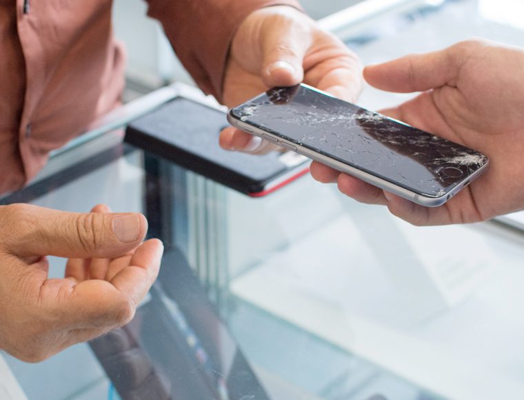 Ein Mann überreicht einem anderen Mann ein kaputtes Handy