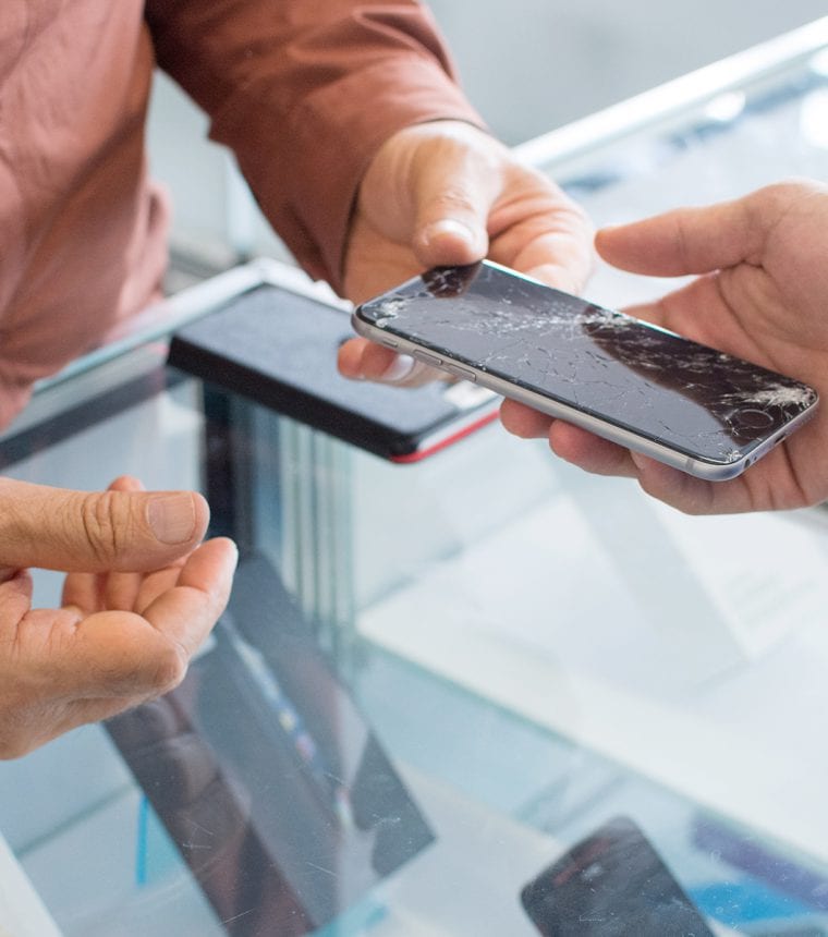 Ein Mann überreicht einem anderen Mann ein kaputtes Handy